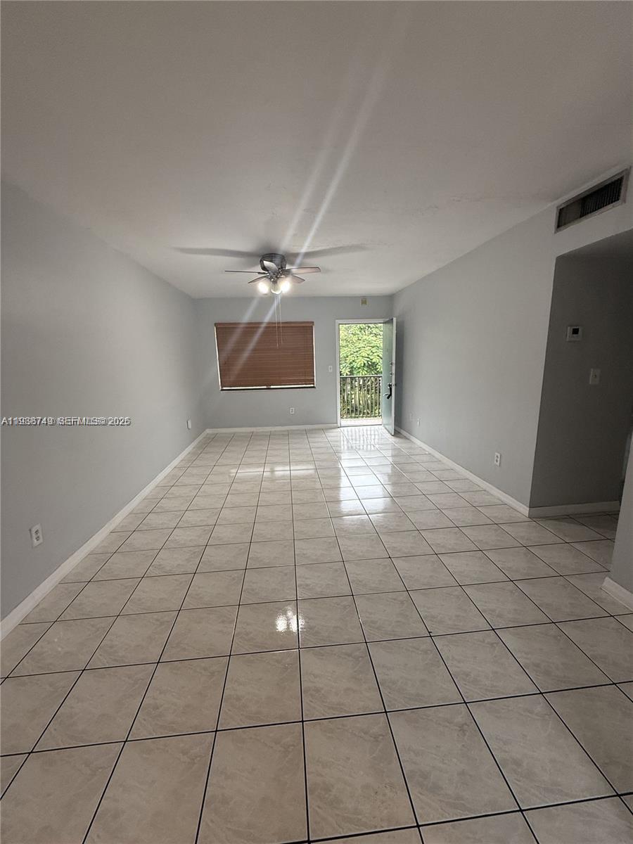An empty room features light-colored tile flooring, a ceiling fan, and a glass-paned exterior door — 7505 SW 82nd St # 314, Miami FL 33143, MIAMI, FL