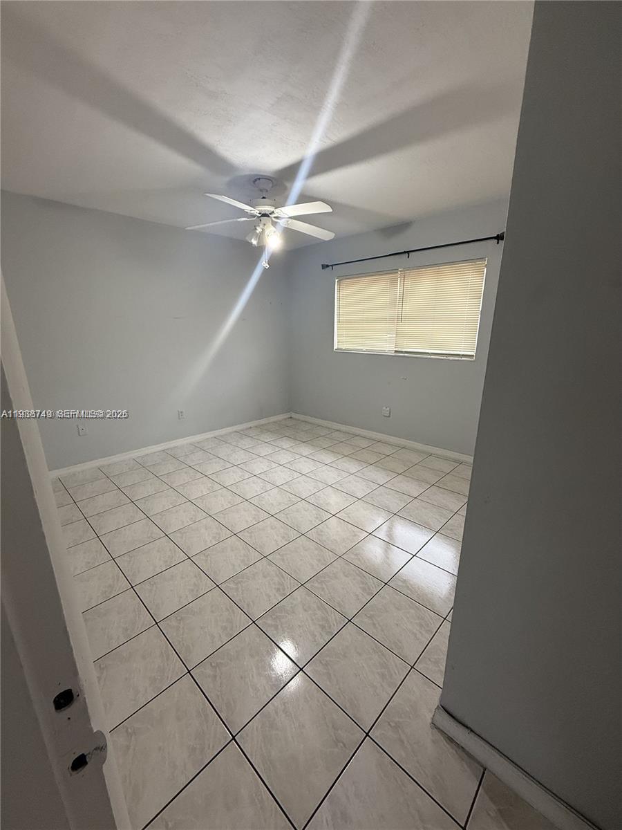 An empty bedroom features light gray walls, white tile flooring, and a ceiling fan — 7505 SW 82nd St # 314, Miami FL 33143, MIAMI, FL