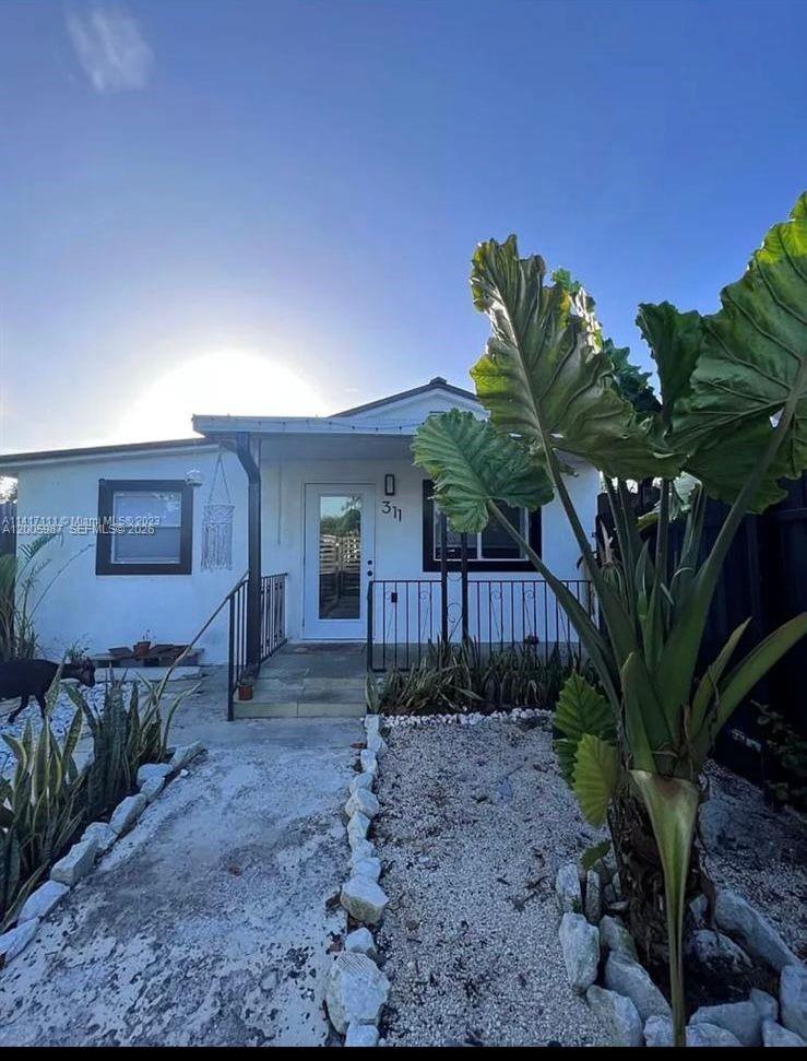A single-story white house with a front porch and a large plant in the yard — 311 NW 32nd Ct, Miami FL 33125, MIAMI, FL