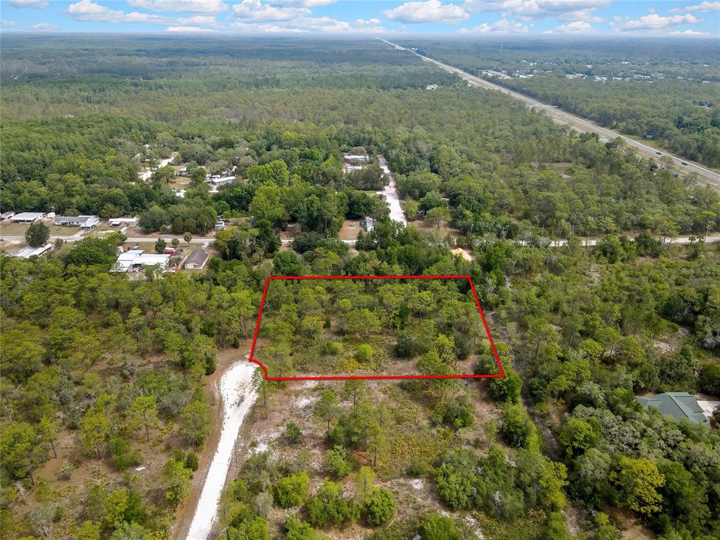 An aerial view shows a rectangular, wooded vacant lot outlined in red near a road — PARALLEL ROAD, WEEKI WACHEE, FL