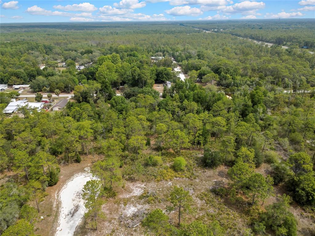 An aerial view shows a wooded lot with a sandy clearing and nearby residential houses — PARALLEL ROAD, WEEKI WACHEE, FL