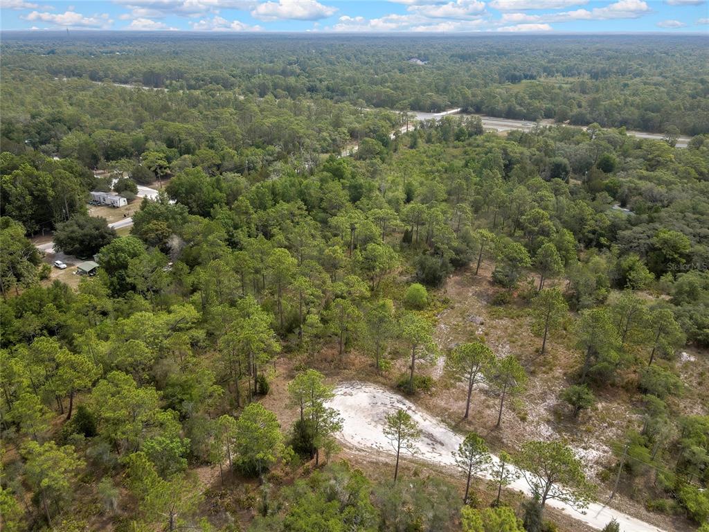 An aerial view shows a wooded lot with a sandy clearing and a nearby road — PARALLEL ROAD, WEEKI WACHEE, FL