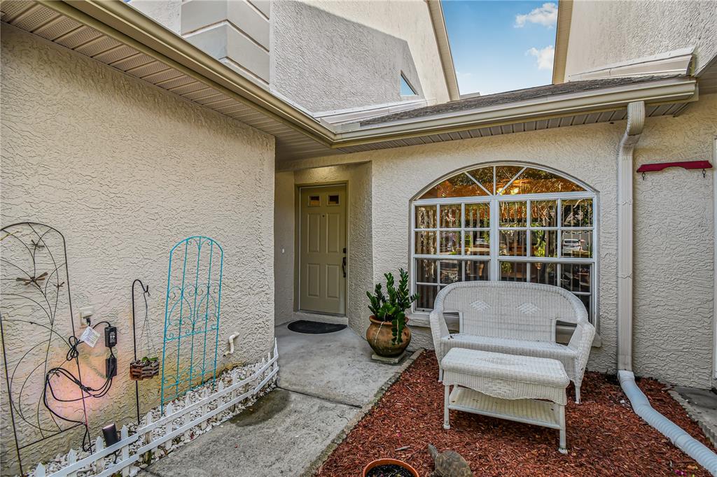 An exterior view of a home entrance with a white bench and a front door — 2586 PINE COVE LANE, CLEARWATER, FL