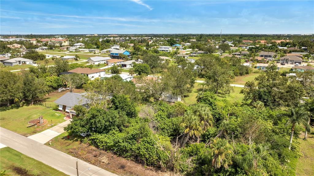An aerial view shows a residential lot with a house, dense trees, and surrounding neighborhood — 2720 POINCIANA COURT, PUNTA GORDA, FL