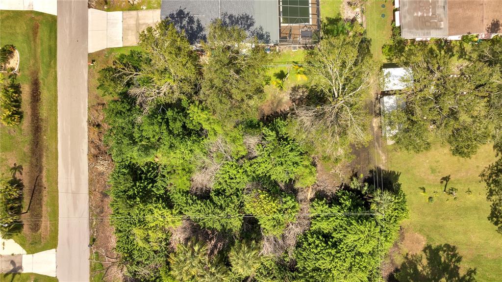 An aerial view shows a heavily wooded residential lot situated between two houses — 2720 POINCIANA COURT, PUNTA GORDA, FL
