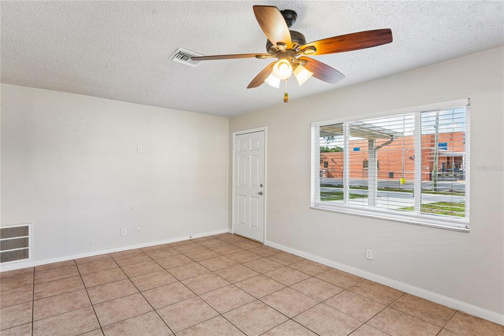 An empty room with tiled floors, a ceiling fan, and a window overlooking a building — 6229 50TH AVENUE N, ST PETERSBURG, FL
