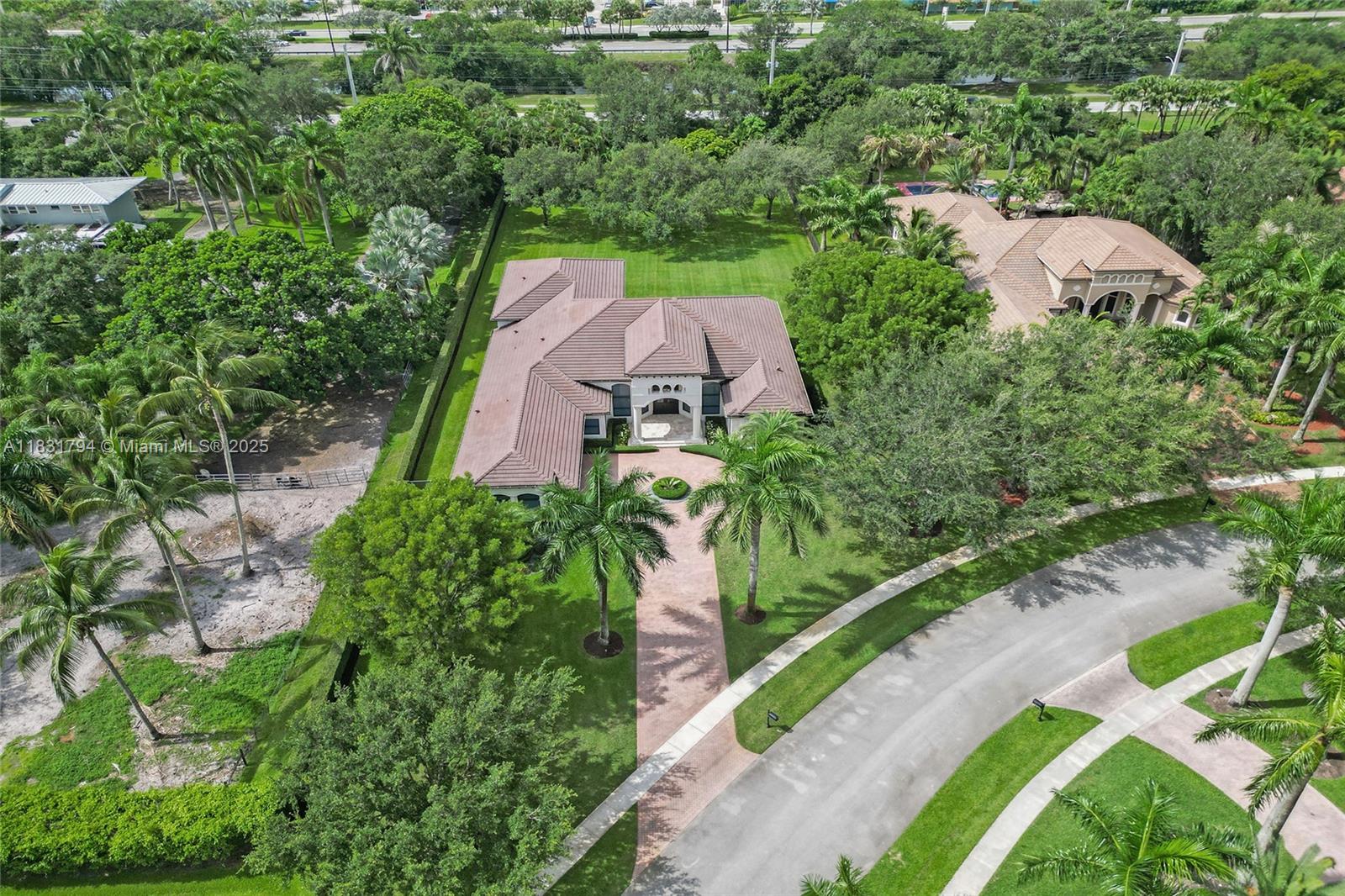 An aerial view shows a large house with a brown tile roof and paved driveway — 11056 Blackhawk Blvd, Davie FL 33328, DAVIE, FL