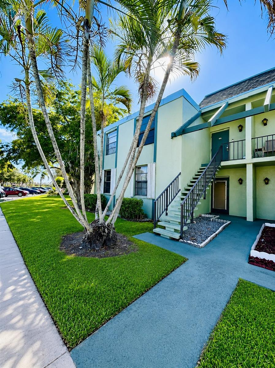 A two-story light green apartment building features an exterior staircase and palm trees in front — 7396 NW 18th St # 101, Margate FL 33063, MARGATE, FL
