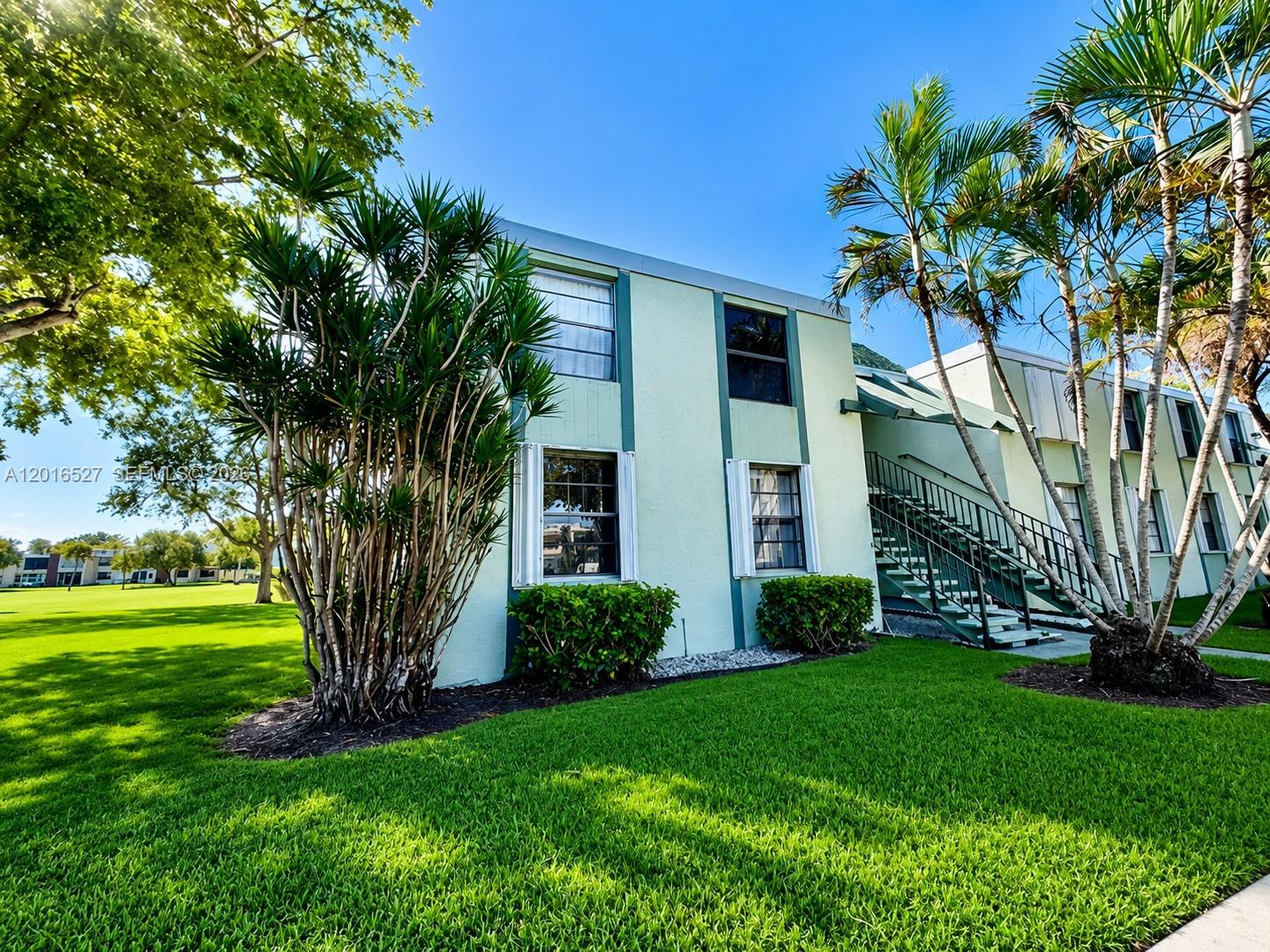 A two-story light green apartment building with an exterior staircase and palm trees — 7396 NW 18th St # 101, Margate FL 33063, MARGATE, FL