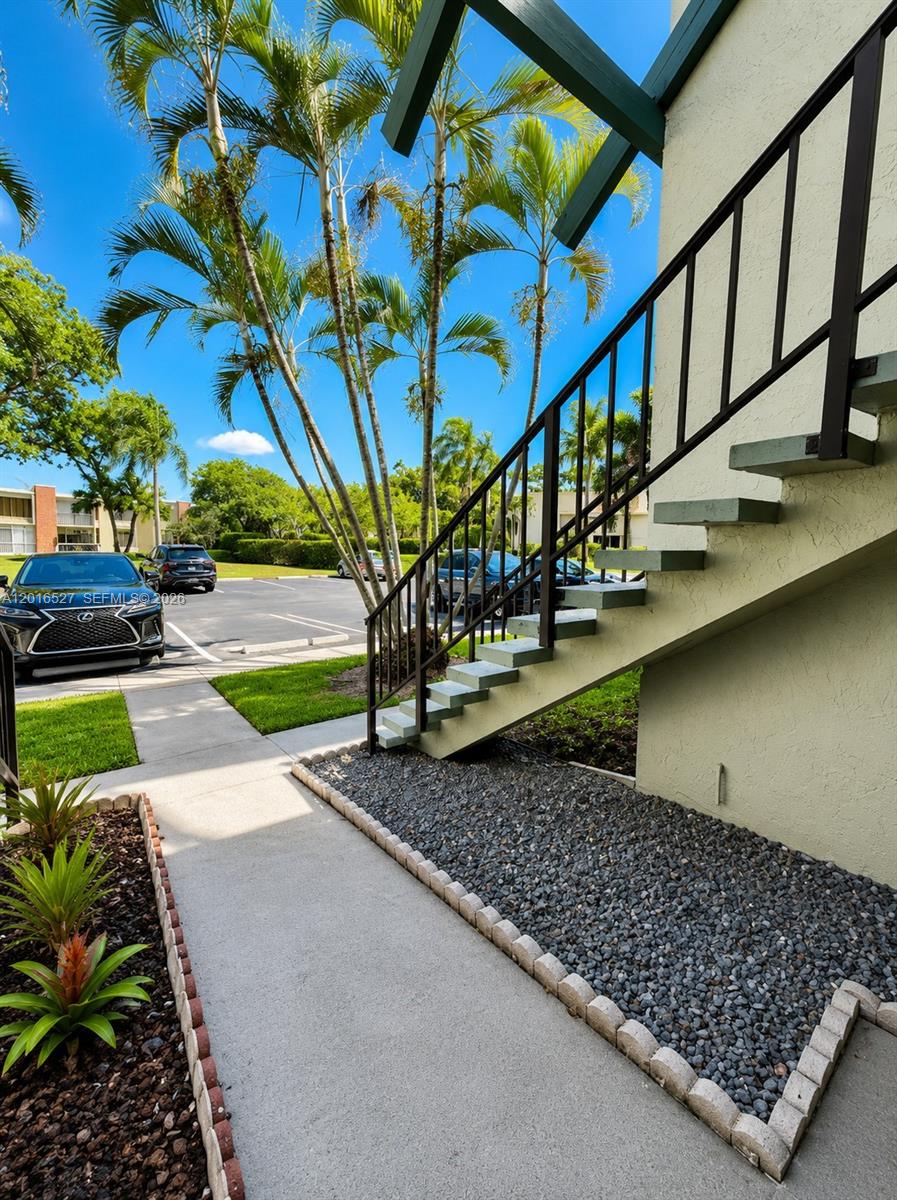 An exterior view shows a concrete staircase with a metal railing beside a parking lot — 7396 NW 18th St # 101, Margate FL 33063, MARGATE, FL