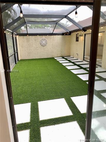 A screened-in patio features artificial turf and square white pavers arranged in a grid pattern — 23277 Barlake Drive, Boca Raton FL 33433, BOCA RATON, FL