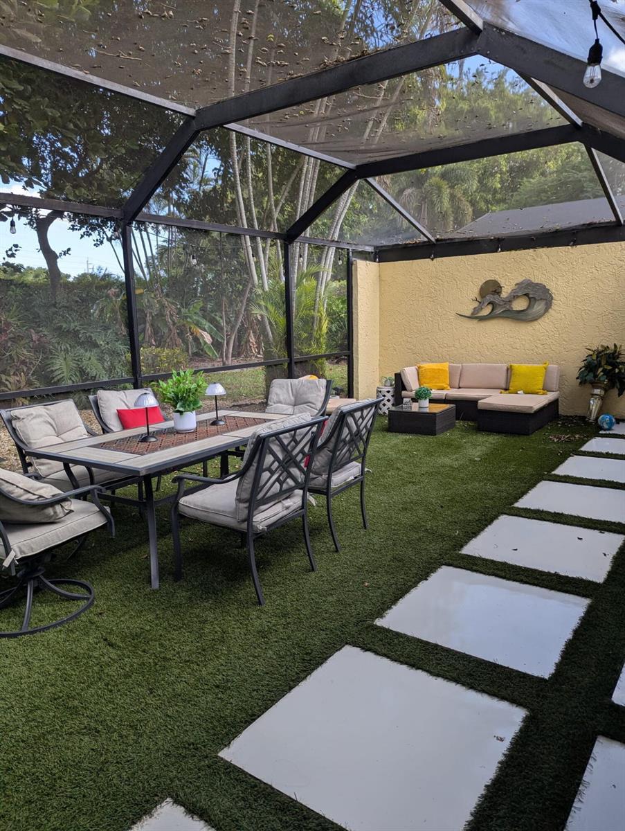A screened-in patio features a dining set, lounge furniture, and pavers set in artificial turf — 23277 Barlake Drive, Boca Raton FL 33433, BOCA RATON, FL