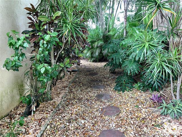 A stone path winds through a lush garden with tropical plants and gravel ground cover — 23277 Barlake Drive, Boca Raton FL 33433, BOCA RATON, FL