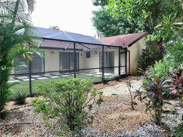 A screened-in patio with artificial turf overlooks a gravel yard and lush landscaping — 23277 Barlake Drive, Boca Raton FL 33433, BOCA RATON, FL
