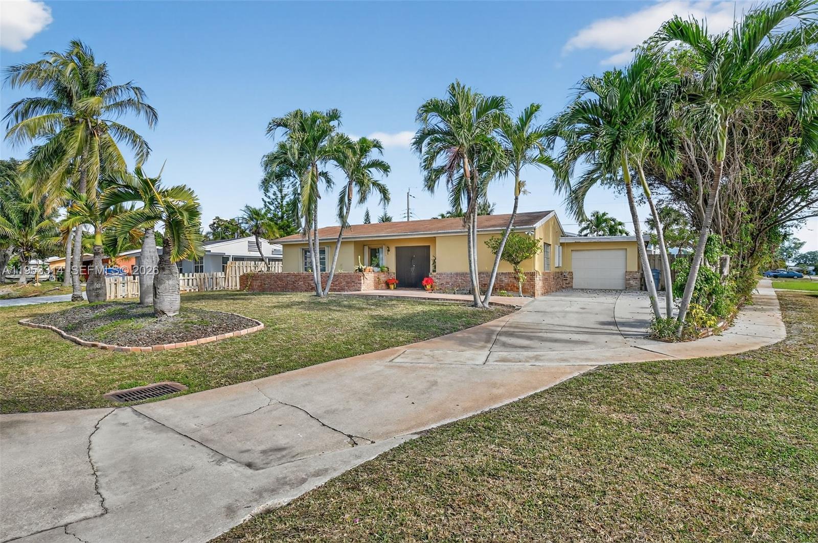 A single-story yellow house with a brick base, a concrete driveway, and several palm trees — 1712 High Ridge Rd, Lake Worth FL 33461, LAKE WORTH, FL