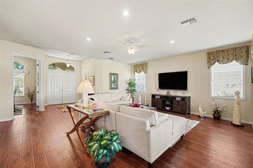 A living room features light-colored furniture, a television console, and wood flooring — 4287 N COURSE LANE, AVON PARK, FL