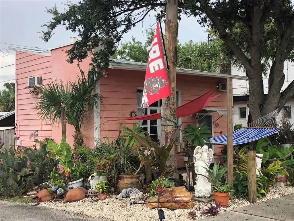 A pink house features a front yard with tropical plants, a hammock, and a memorial marker — 416 PRINCESS STREET, CLEARWATER, FL