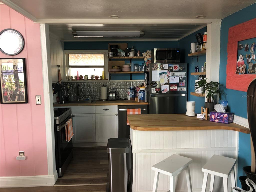 A kitchen features white cabinets, a wood countertop, open shelving, and a breakfast bar area — 416 PRINCESS STREET, CLEARWATER, FL