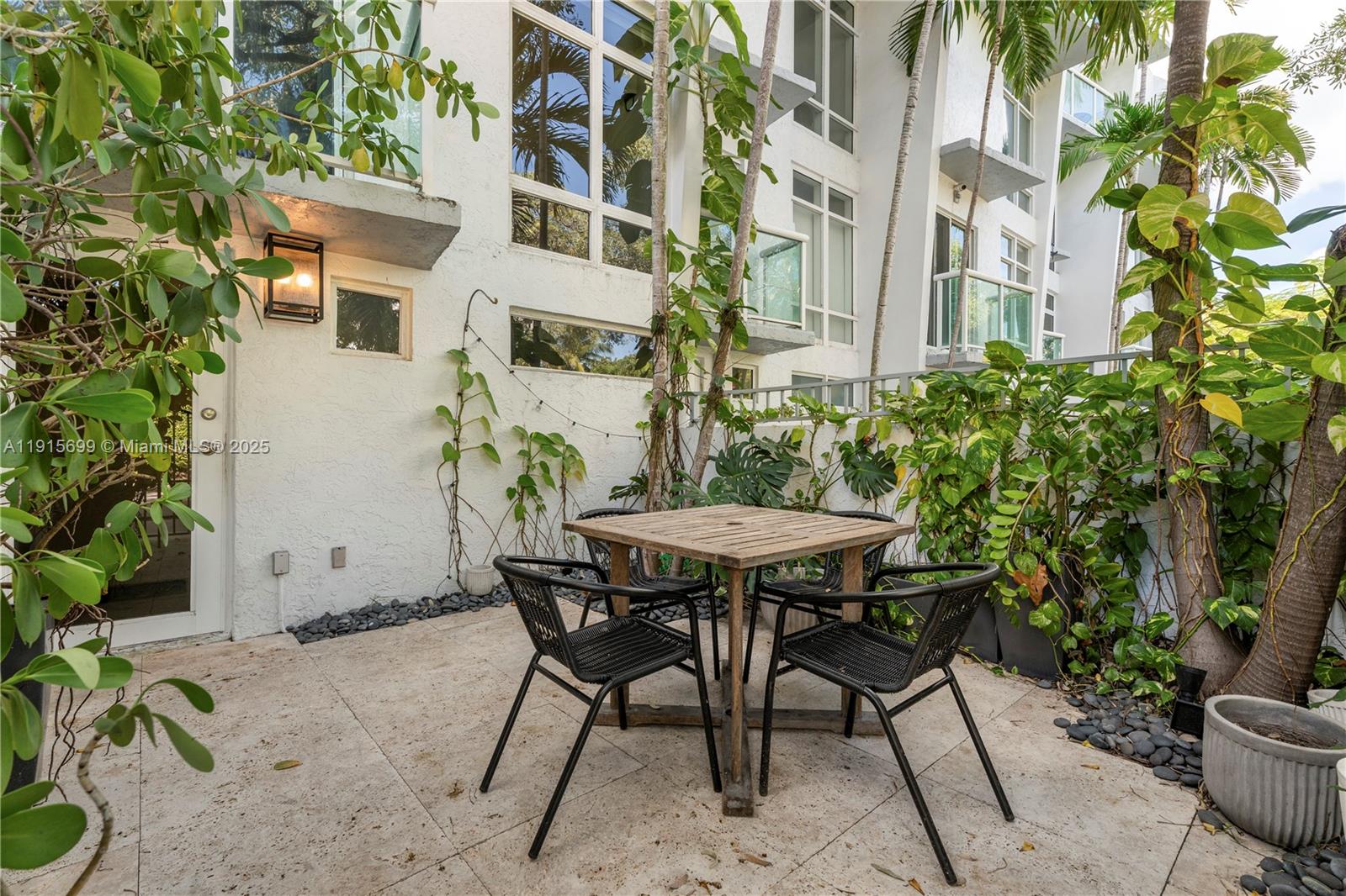 A patio features a wooden table with four black chairs against a white building — 1853 Jefferson Ave # 6, Miami Beach FL 33139, MIAMI BEACH, FL