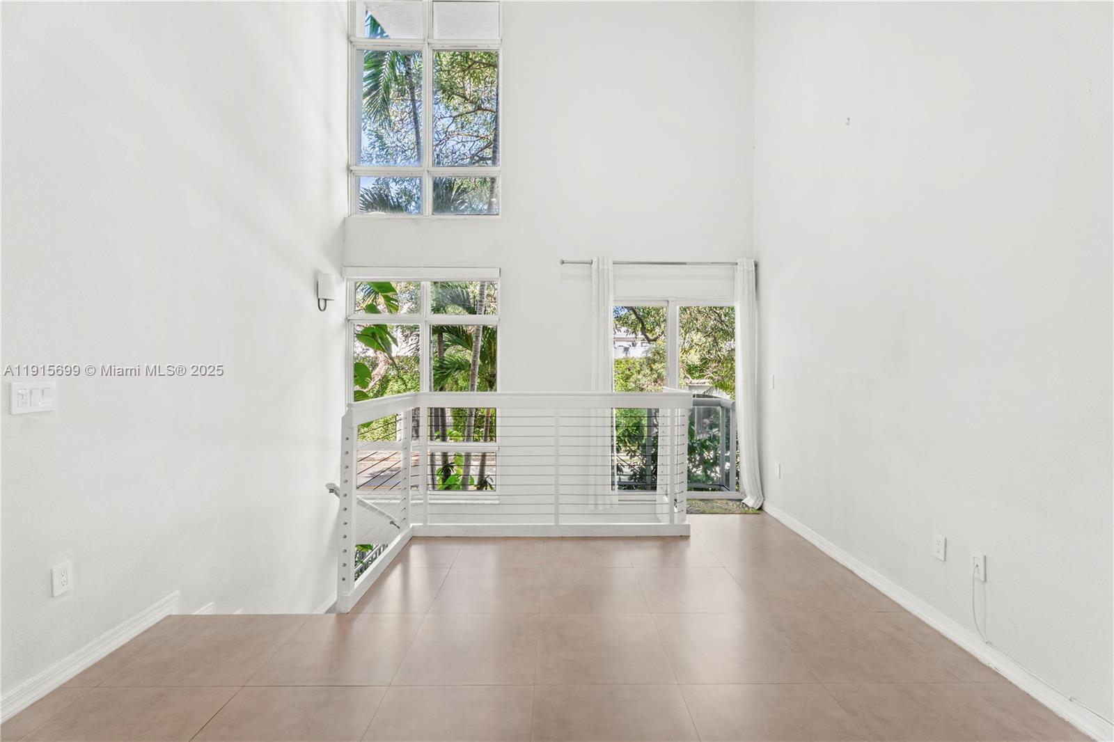 An interior view of a landing with tile flooring, a white railing, and tall windows — 1853 Jefferson Ave # 6, Miami Beach FL 33139, MIAMI BEACH, FL