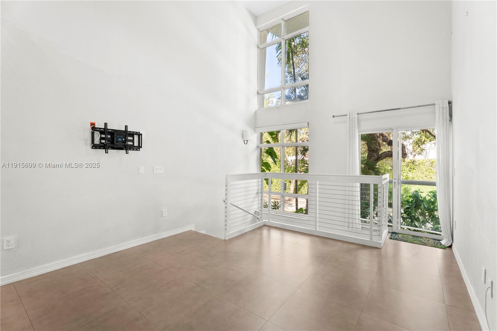 A bright room features high ceilings, large windows, tile flooring, and a white railing — 1853 Jefferson Ave # 6, Miami Beach FL 33139, MIAMI BEACH, FL