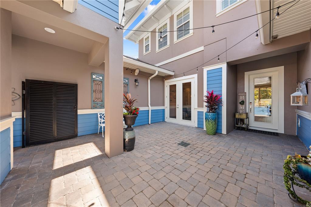 A paved courtyard features a covered entryway, blue siding accents, and potted plants — 12735 BANTING TERRACE, ORLANDO, FL