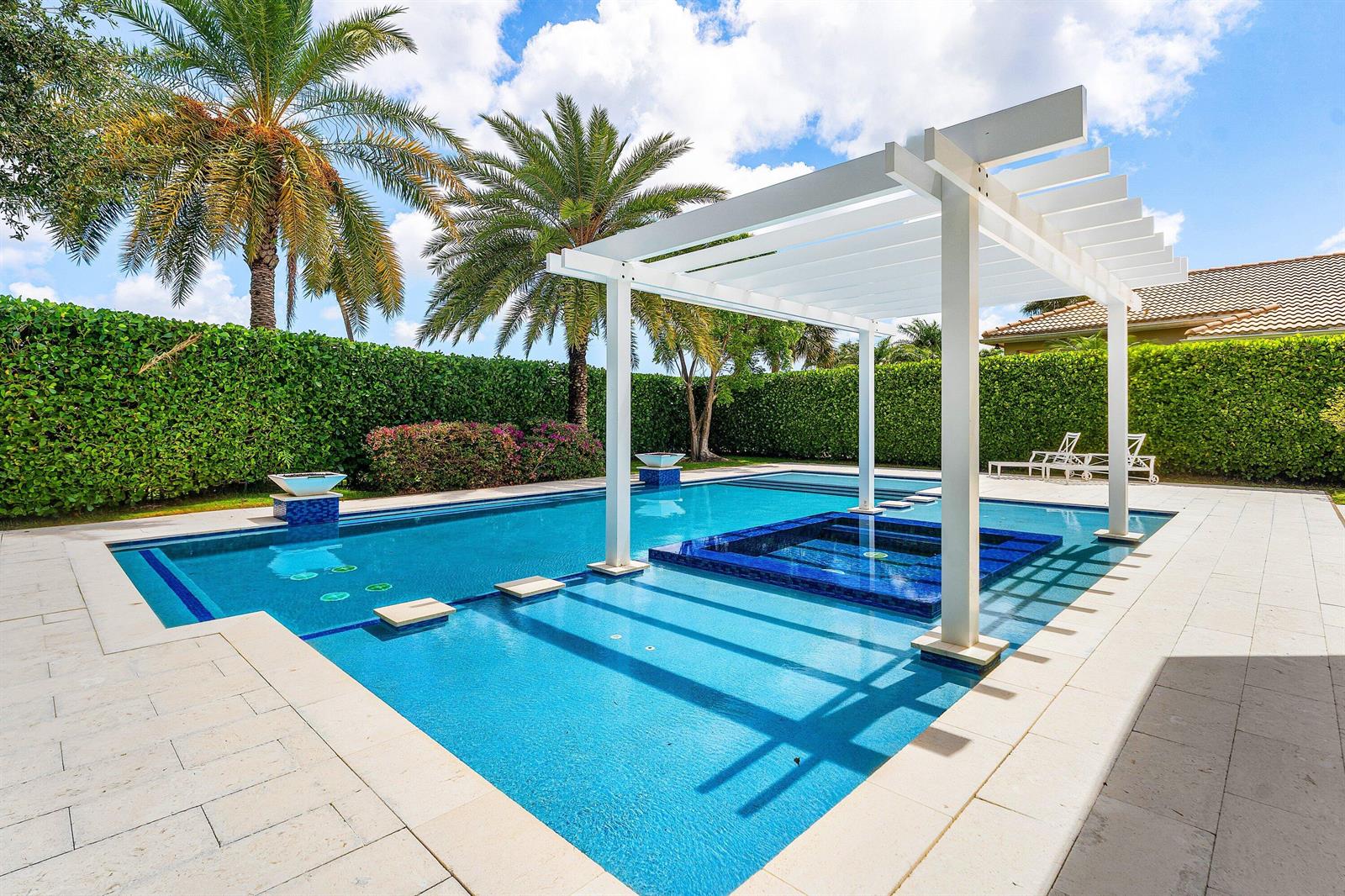 A swimming pool with a built-in spa and a white pergola sits in a backyard — 131 Carmela Court, Jupiter FL 33478, JUPITER, FL