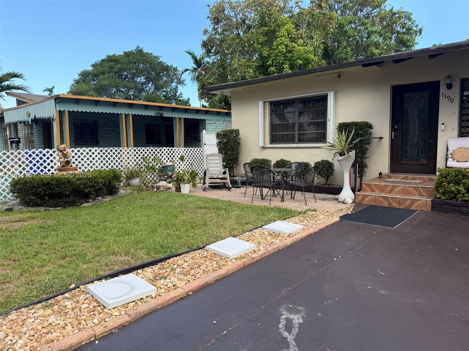 The exterior of a single-story house features a front patio, a small lawn, and driveway — 1190 NW 50th St, Miami FL 33127, MIAMI, FL