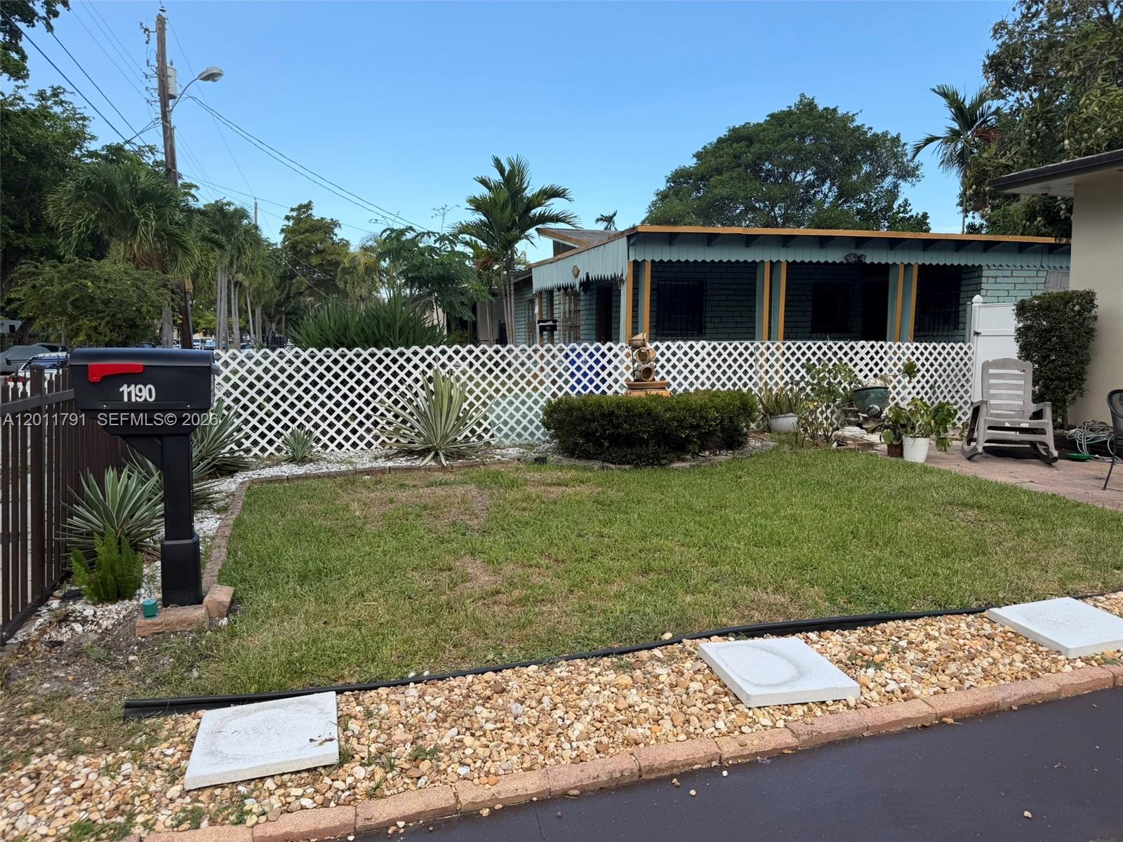 A front yard with a lawn, landscaping, a white lattice fence, and a mailbox — 1190 NW 50th St, Miami FL 33127, MIAMI, FL
