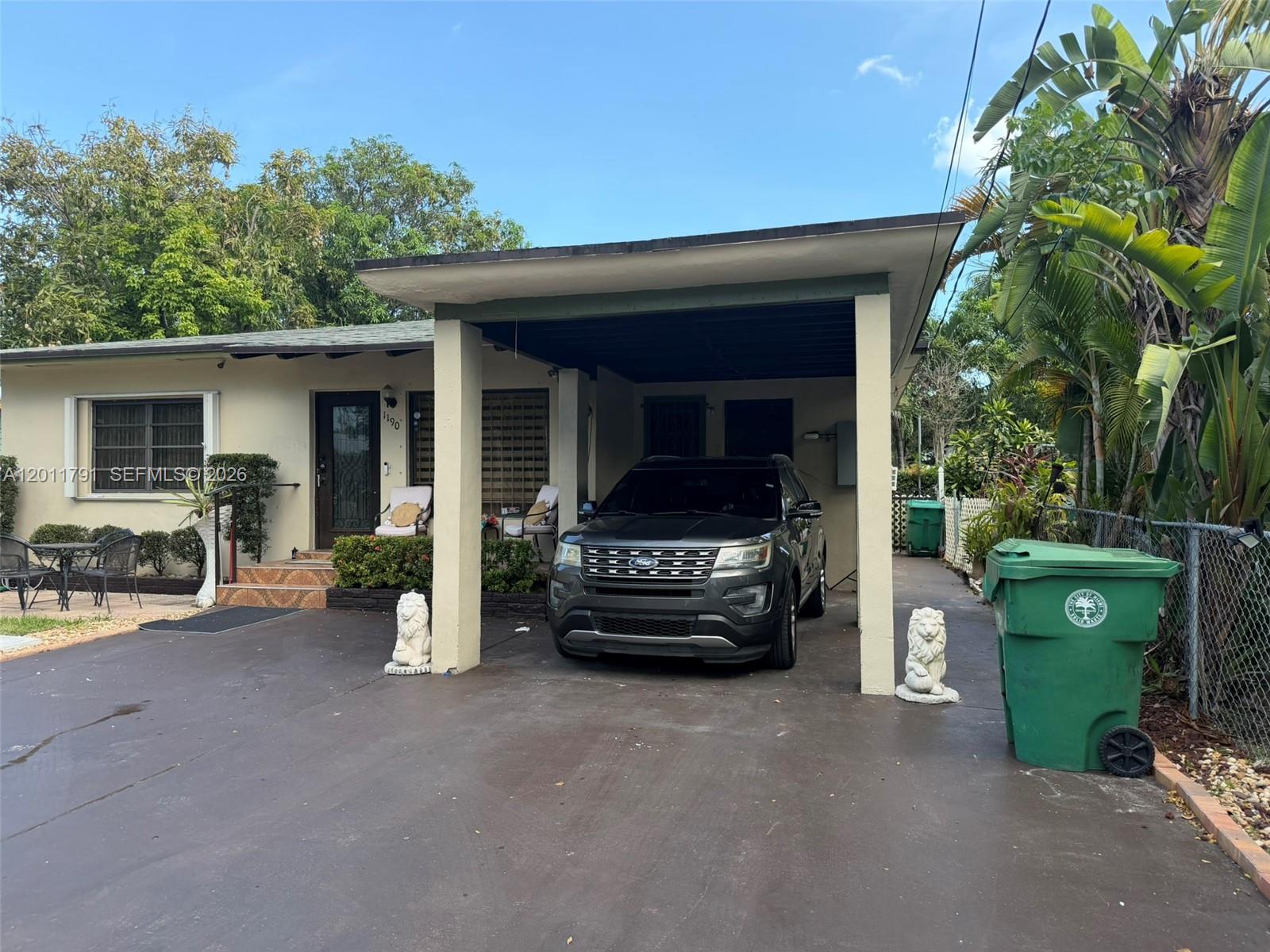 A single-story house features a carport with a parked SUV and two lion statues — 1190 NW 50th St, Miami FL 33127, MIAMI, FL