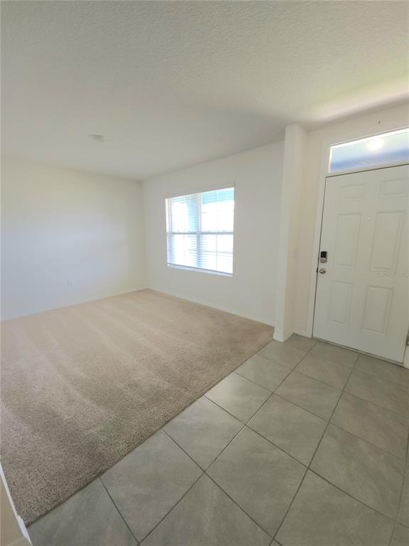 An entryway with tile flooring leads into a carpeted living area with a single window — 575 TORTUGAS STREET, HAINES CITY, FL