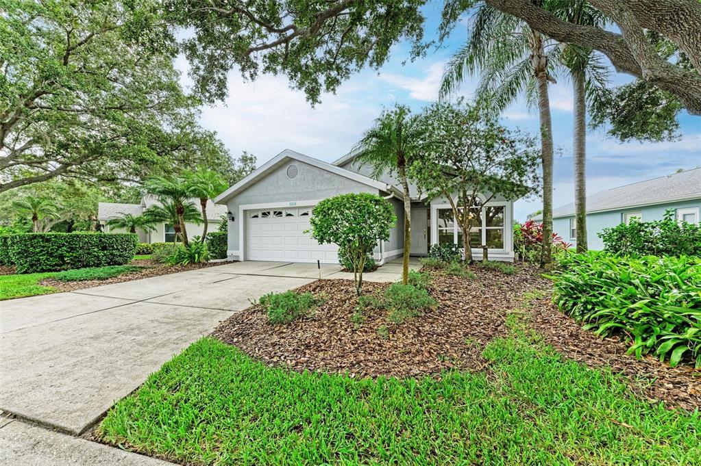 A single-story house with a white garage door, gray siding, and a landscaped front yard — 4936 LINSEY COURT, SARASOTA, FL