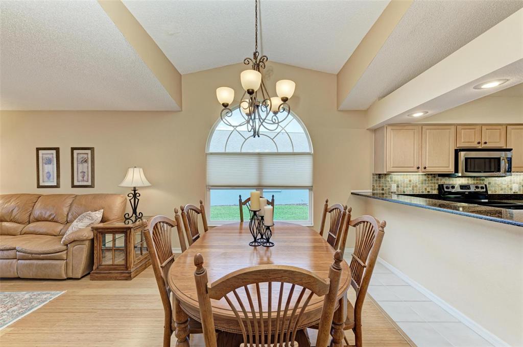 A dining area with a wooden table and chairs sits adjacent to a living room — 4936 LINSEY COURT, SARASOTA, FL