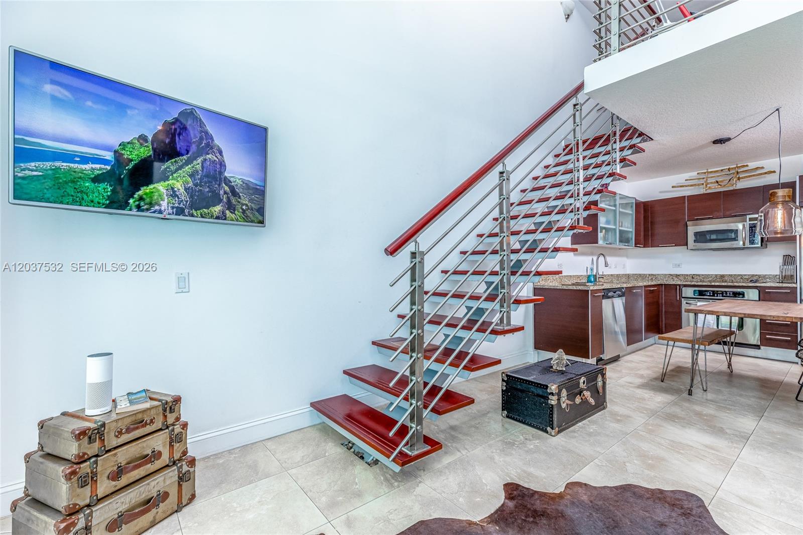 A modern living area features a floating staircase, tiled floors, and an open-concept kitchen — 41 SE 5th St # 706, Miami FL 33131, MIAMI, FL