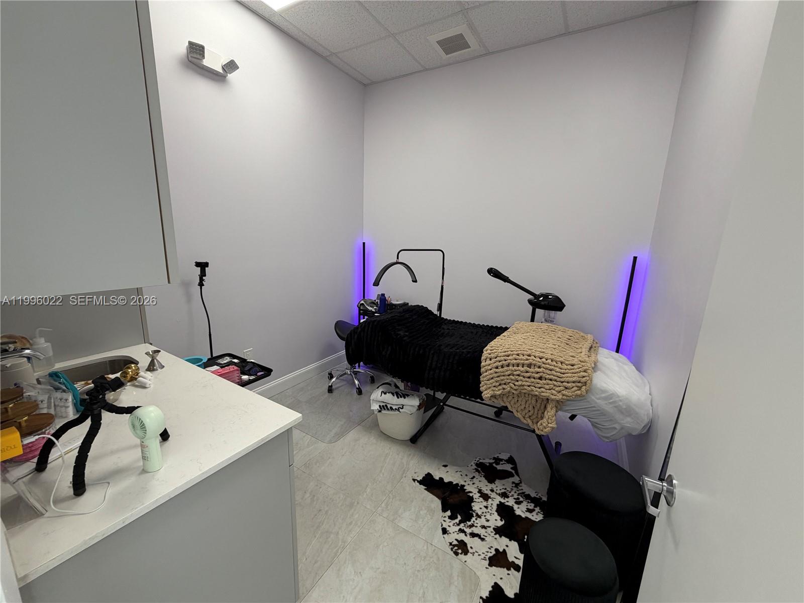 A small treatment room features a massage table, vanity sink, and purple accent lighting — MED SPA FOR SALE, Miramar FL 33025, MIRAMAR, FL