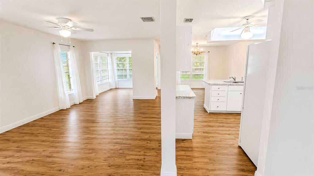 An open-concept living area with wood-look flooring leads into a kitchen with white cabinets — 1624 WHITEHEAD DRIVE UNIT 320, SARASOTA, FL