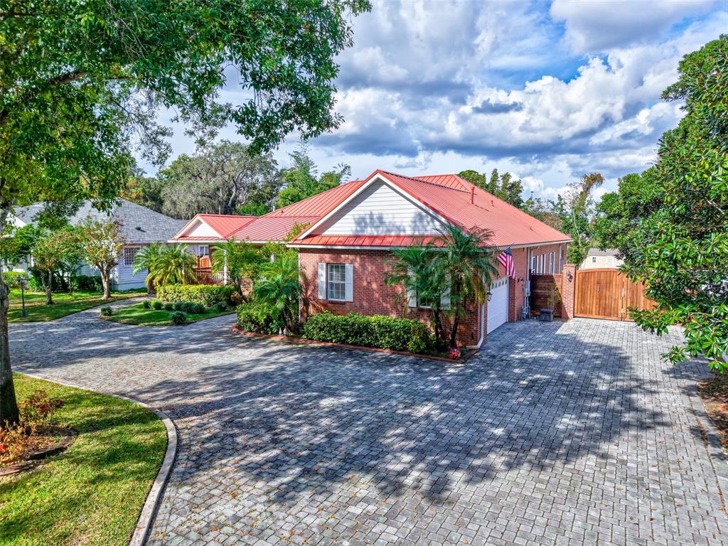 A brick house with a red metal roof and a large paved driveway — 9663 GOTHA ROAD, WINDERMERE, FL