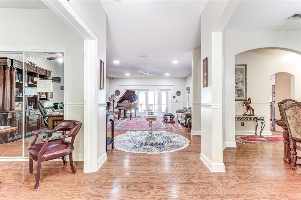 A view through a foyer into a living area with a grand piano and hardwood floors — 9663 GOTHA ROAD, WINDERMERE, FL