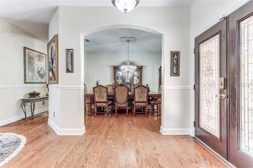 An entryway with hardwood floors leads through an arched opening into a formal dining room — 9663 GOTHA ROAD, WINDERMERE, FL