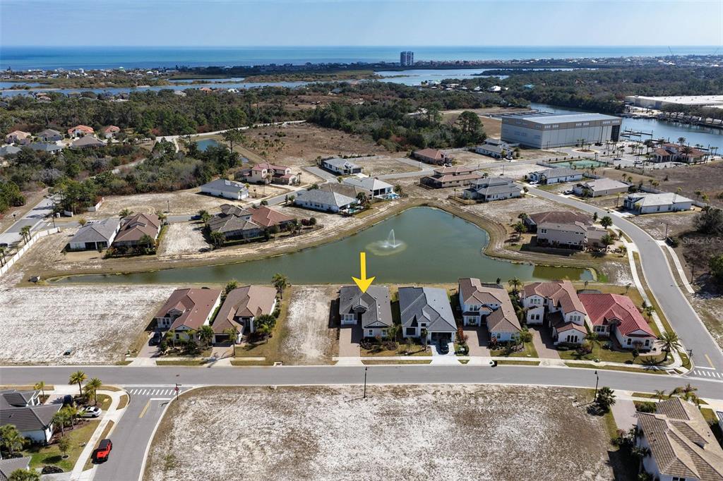 An aerial view shows a residential house with a yellow arrow facing a pond — 122 DEL PALMA DRIVE, PALM COAST, FL