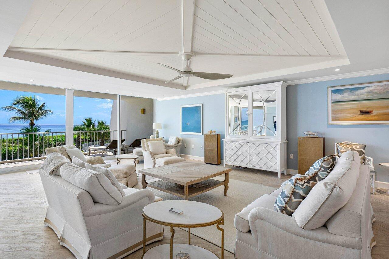 A bright living room features a vaulted ceiling, light blue walls, and a balcony view — 2001 SE Sailfish Point Boulevard # 212, Stuart FL 34996, STUART, FL