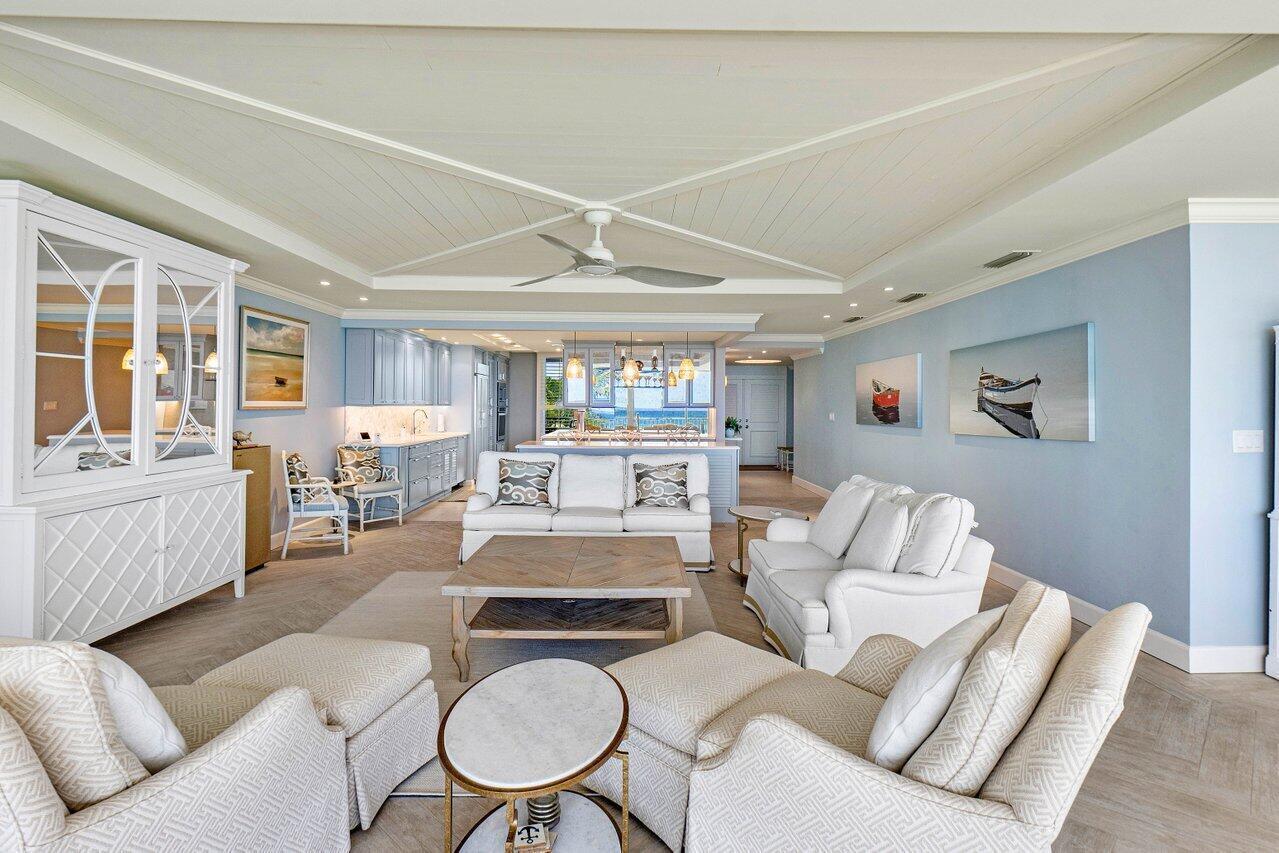 A bright, coastal-style living room features light blue walls, white furniture, and a coffered ceiling — 2001 SE Sailfish Point Boulevard # 212, Stuart FL 34996, STUART, FL