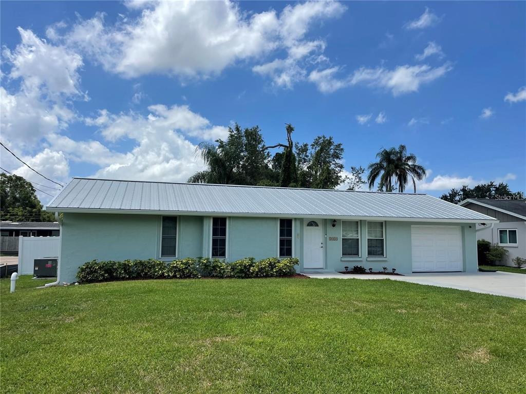 A light green, single-story house with a metal roof and an attached one-car garage — 3410 BAY STREET, SARASOTA, FL