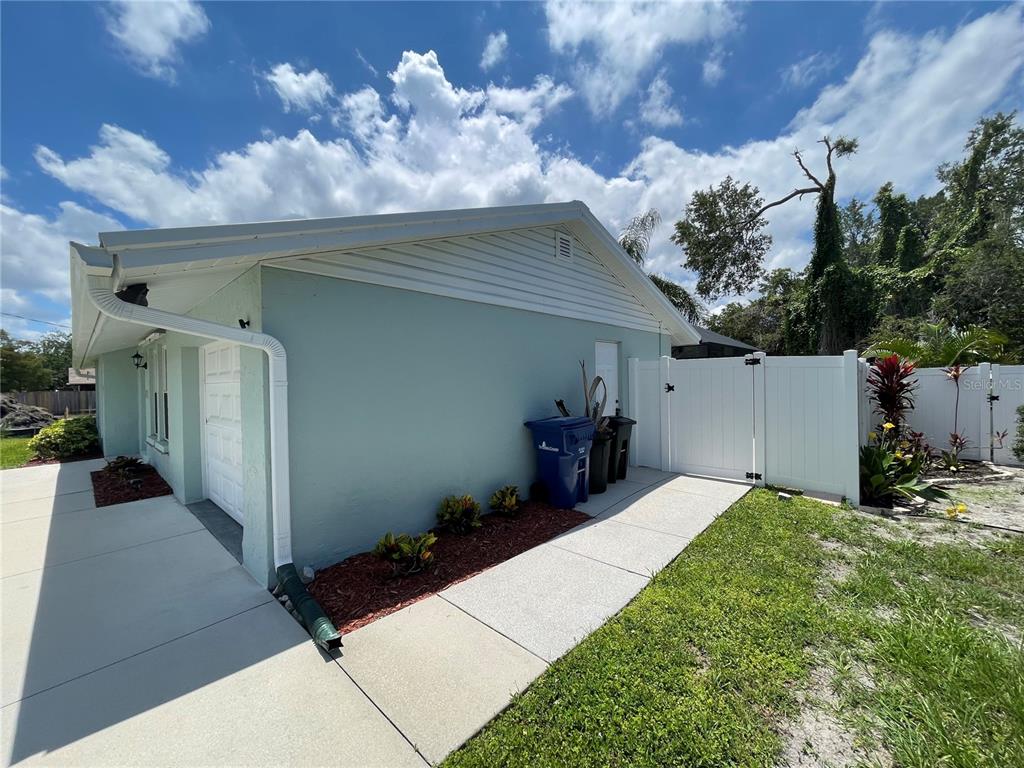The exterior of a light blue house features a white fence and a concrete walkway — 3410 BAY STREET, SARASOTA, FL