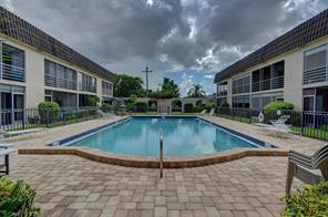 A rectangular swimming pool sits between two multi-story apartment buildings with a paved patio area — 342 Southwind Drive # 216, North Palm Beach FL 33408, NORTH PALM BEACH, FL