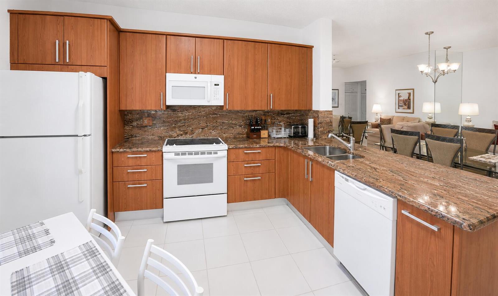 A kitchen with wood cabinets, granite countertops, white appliances, and tile flooring — 6566 Via Regina # 6566, Boca Raton FL 33433, BOCA RATON, FL