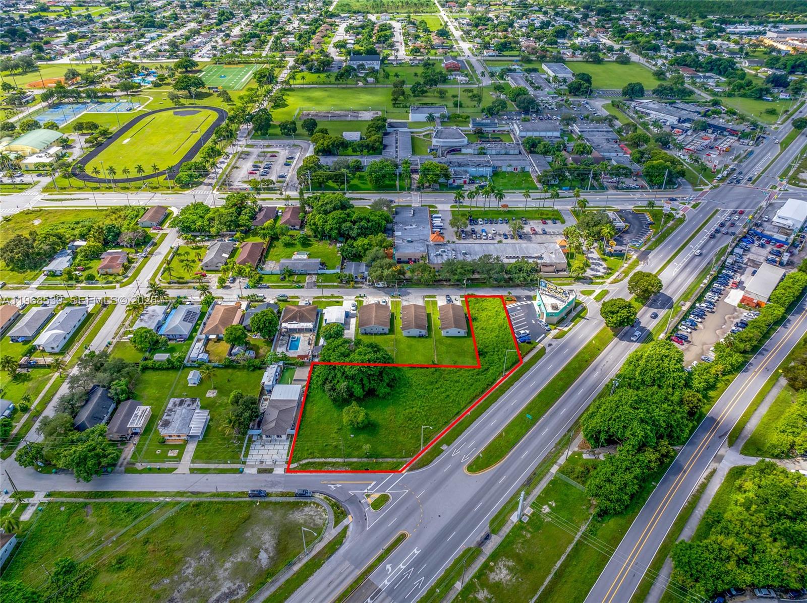 An aerial view shows a vacant, grass-covered lot outlined in red next to a roadway — 214 S Dixie Hwy, Miami FL 33189, MIAMI, FL