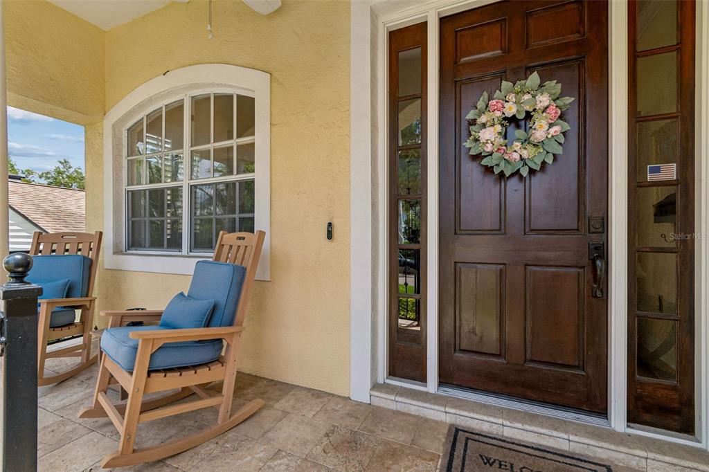A covered front porch features a wooden rocking chair, a dark wood door, and tile flooring — 107 BERMUDA AVENUE, TAMPA, FL