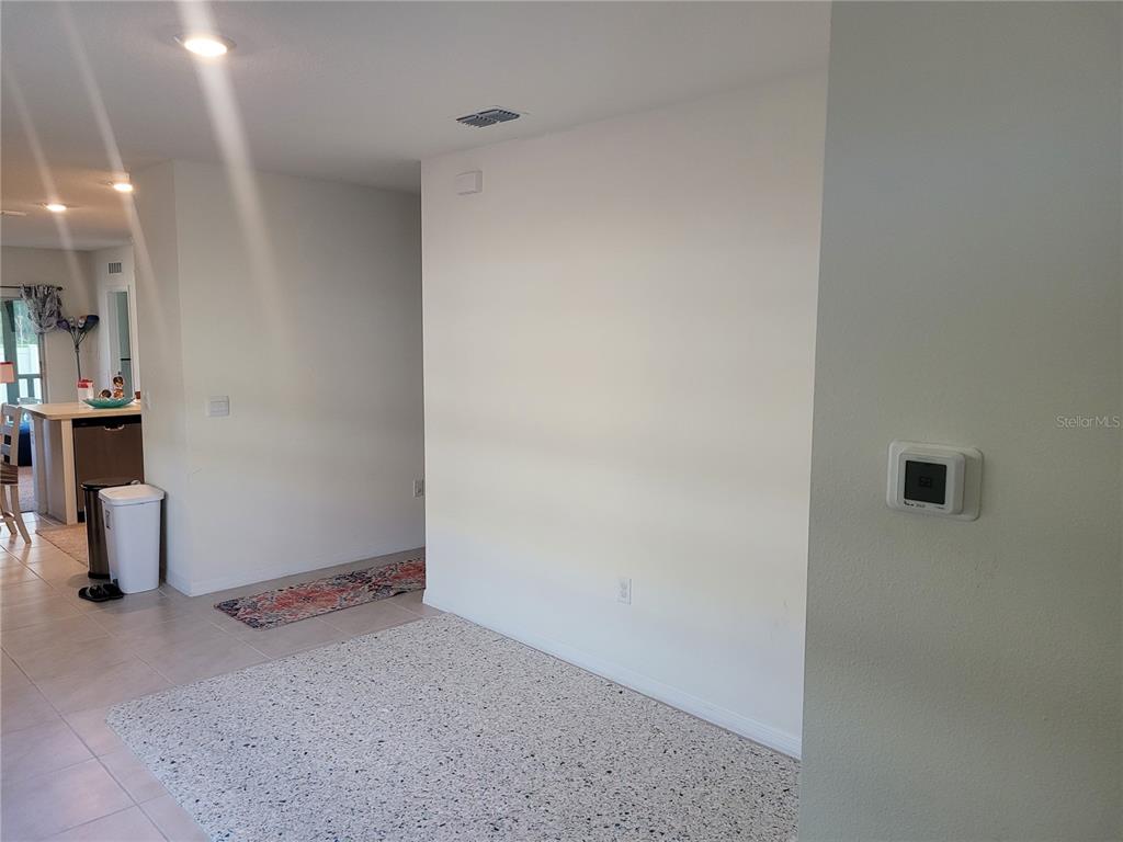 A view of an interior space with a large blank wall and a wall-mounted thermostat — 2763 REDDISH EGRET BEND, HARMONY, FL