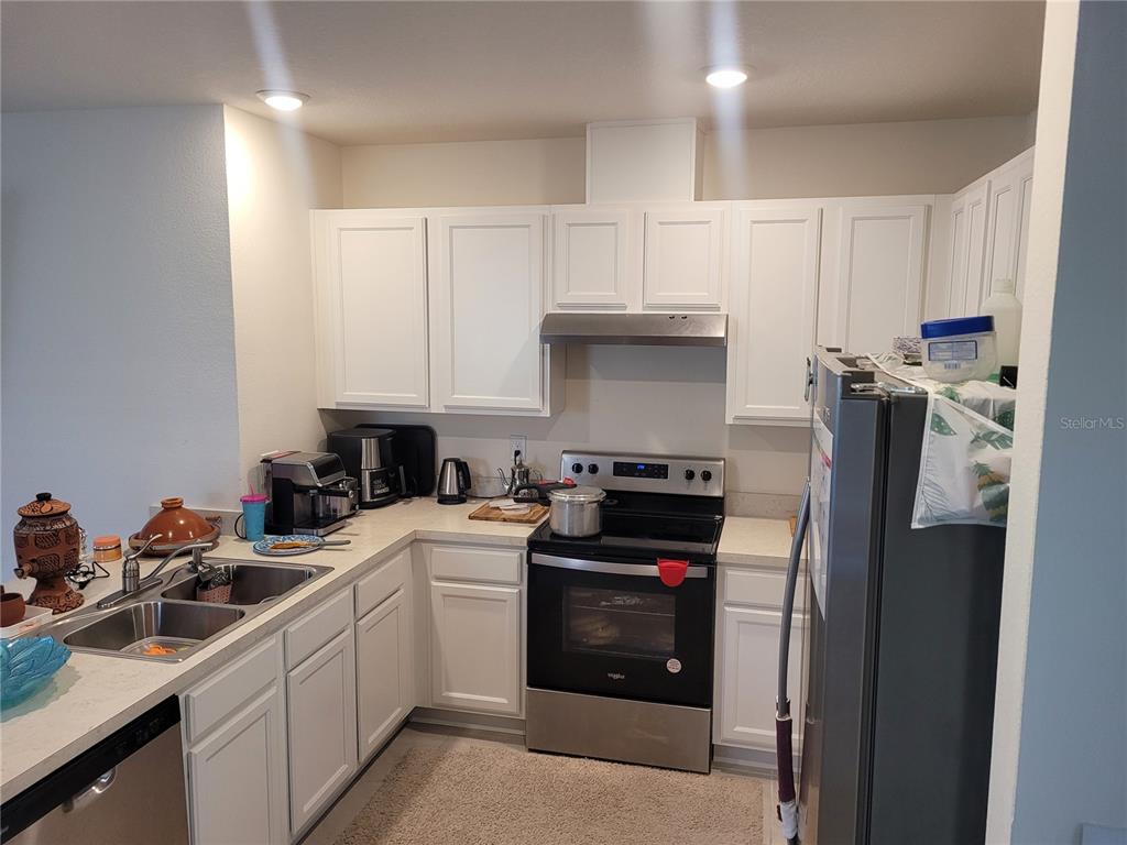 A kitchen features white cabinets, stainless steel appliances, and light-colored countertops — 2763 REDDISH EGRET BEND, HARMONY, FL